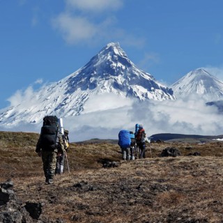 Hiking on Kamchatka Peninsula: group of tourists and travelers with backpacks behind the shoulders