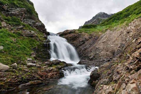 Summer mountain landscape of Kamchatka: beautiful view of picturesque waterfall in Mountain Range
