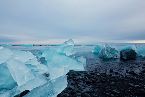Vast icy shoreline seen with scattered icebergs under a wide overcast sky, Expansive icy scene with