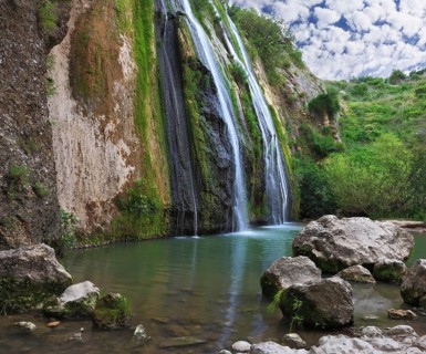 Three parallel streams of water running down the steep slope and fall in oval pool. Three-jet