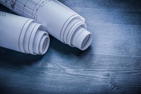 Rolled white blueprints on wood board