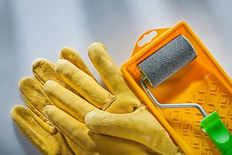 Leather safety gloves paint tray roller on white surface