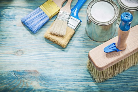 Paint cans brushes on wooden board top view construction concept