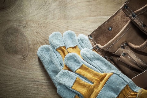 Leather building belt safety gloves on wooden board