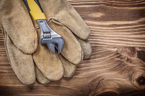 Safety gloves adjustable wrench on wooden board construction concept