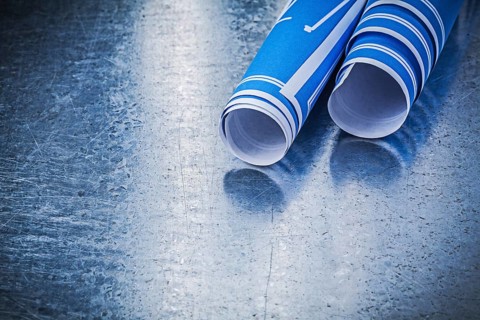 Stack of blue construction plans on metallic background building concept