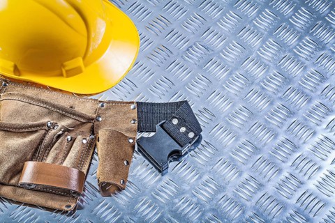Tool belt building helmet on grooved metal plate construction concept