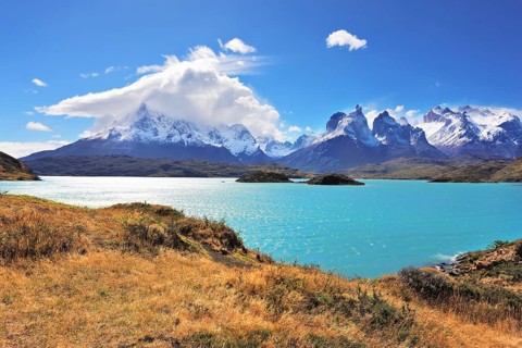 The strong wind drives turquoise waves on the lake, grandiose rocks Los Kuernos are covered with