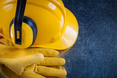 Hard hat ear muffs and leather protective gloves on metallic background close up view construction