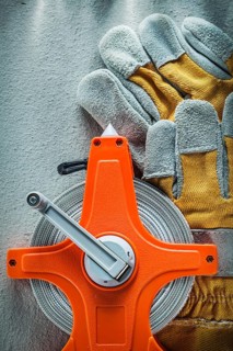 Pair of protective gloves measuring tape on concrete background