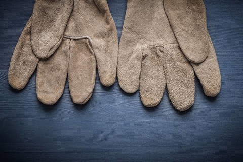 Pair of protective working gloves on wooden board