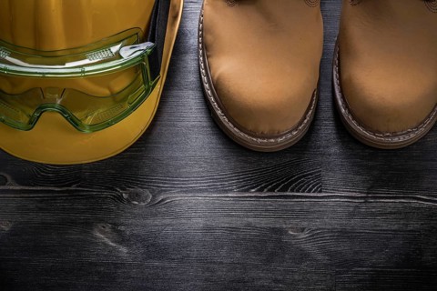 Protective goggles hard hat safety boots on wood board