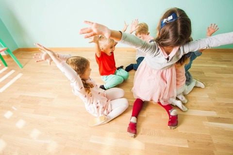 Kids with irresistable joy playing on a wooden floor at the preschool. Children full of fun and