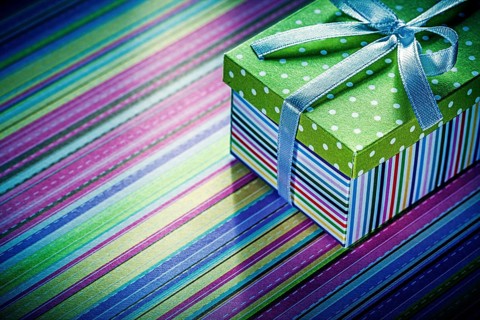 Wrapped cardboard box with gift on striped tablecloth celebrations concept