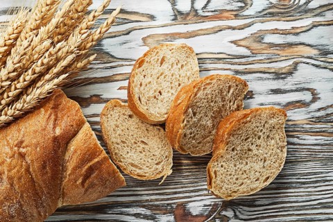 Sliced bread ripe rye ears on wooden surface