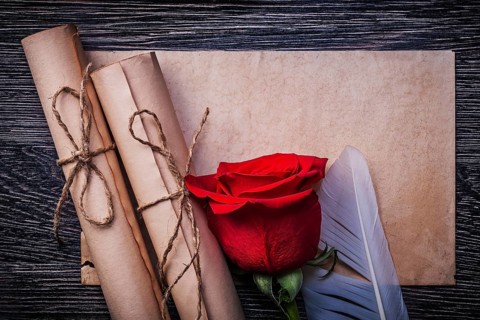 Vintage paper rolls red natural rose on wooden background