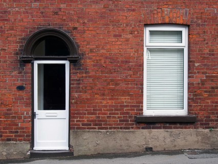 White front door and window of a typical old brick british terraced house with white windows and