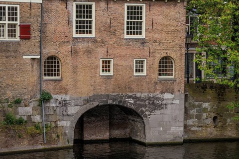 Brick wall with several windows and a large arch leading into the water, Rotterdam, Netherlands