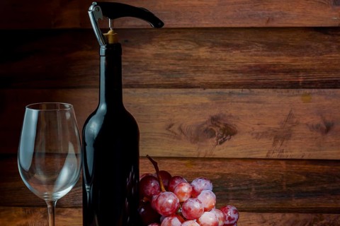 Wine bottle with corkscrew, empty wineglass and bunch of grapes on wooden background, ready for