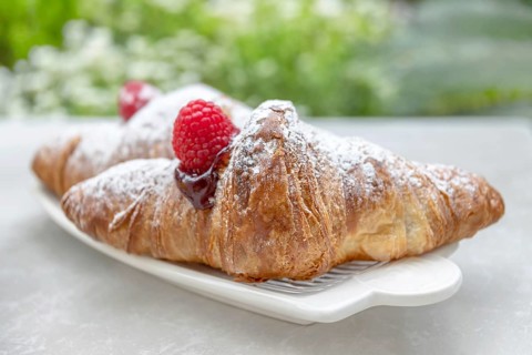 Croissants with jam and berries for Breakfast. Behind, a defocus background