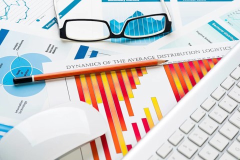Business workplace with keyboard glasses and financial documents on table