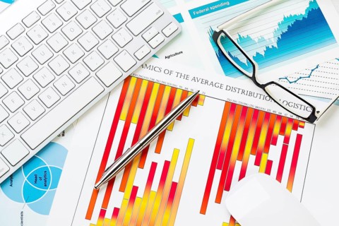 Business workplace with keyboard glasses and financial documents on table