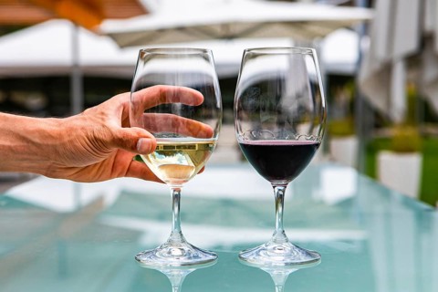 Man hand on white wine glass, pair of white and red wines glasses close up selective focus,