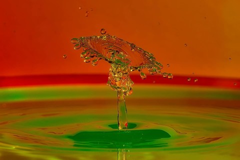Close-up of a coloured water splash with green and orange that looks like a plastic sculpture,
