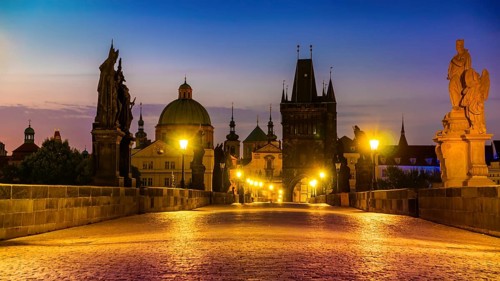 Charles Bridge illuminated with street lights at sunrise, Prague