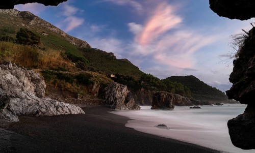 Silhouette frame of a beach cave and view Marina di Maratea Beach at sunset