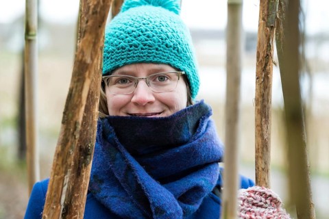 Young woman in winter clothes posing between large bamboo sticks