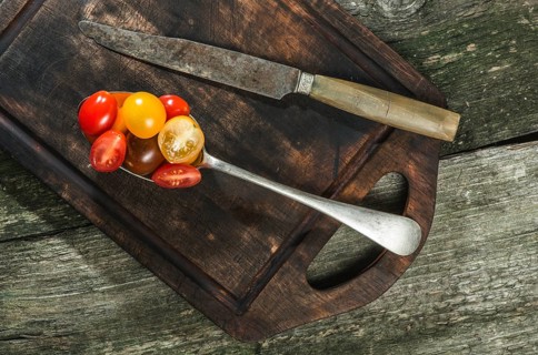Variety of cherry tomatoes in spoon on wood