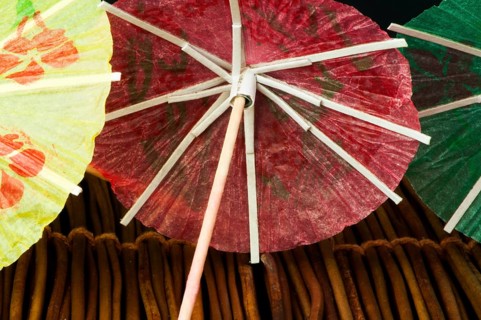 Colorful cocktail umbrellas on wooden base. Close up
