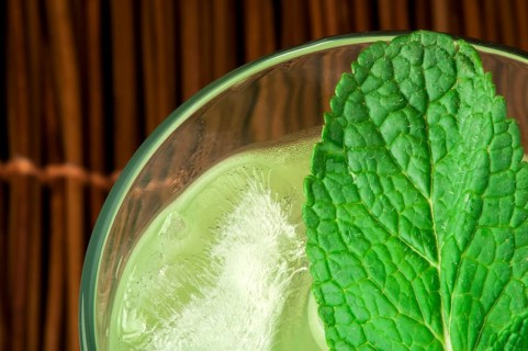 Green cocktail with cubes ice. Close up glass and mint leaves