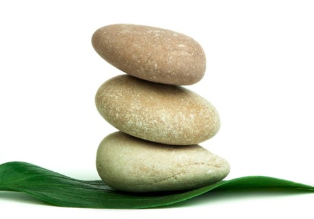 Stacked stones on base of green leafs. White isolated studio shot