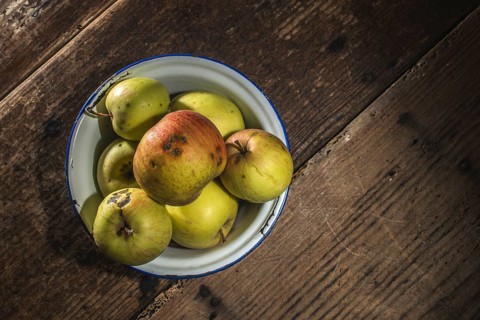 Apples in vintage metal cup on white wooden table