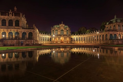 Dresden Zwinger palace panorama with illumination at night and water reflection, Germany