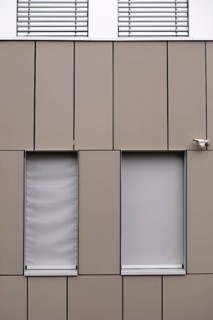 A modern office building façade with sheet metal cladding and an installed surveillance camera