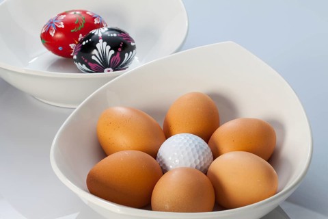 Two white ceramics bowls, easter eggs and golf balls