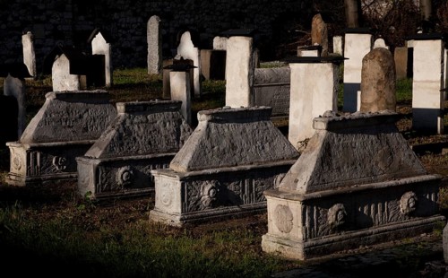 Lined up sarcophagi, tombstones behind them