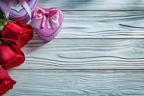 Set of metal heart-shaped present boxes red roses on wooden board celebrations concept