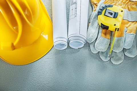 Set of blueprints building helmet safety gloves measuring tape on concrete background