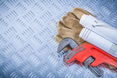 Pipe wrench engineering drawings leather safety gloves on fluted metal plate construction concept
