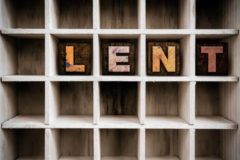 The word LENT written in vintage ink stained wooden letterpress type in a partitioned printer's
