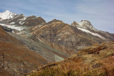 Barren mountain landscape with glaciers and snow-covered peaks under a blue sky, saas fee,