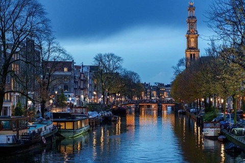 Evening atmosphere with canals, bridge and a tower in the distance, Amsterdam, Netherlands
