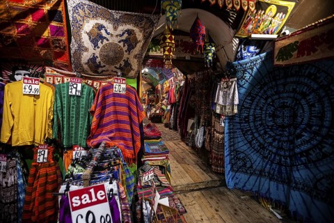 Colorful garments and textiles with sale signs in a vibrant market setting in the London Borough of
