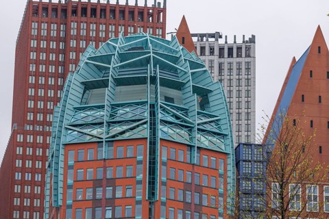 Detailed view of a modern skyscraper with a unique design, surrounded by other buildings in The