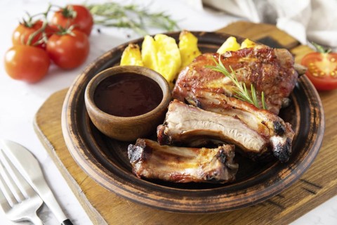 BBQ grilled veal calf brisket meat and french fries potatoes with sauce on a marble tabletop