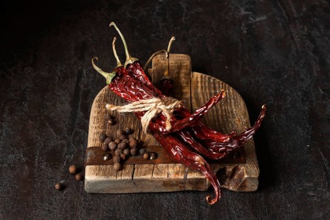 Dried chili peppers on a wooden board, dark photo